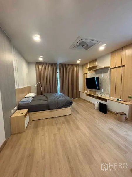独立式住宅 出租在Mueang Nonthaburi, Nonthaburi - 主卧铺木地板，电视墙、内置搁架与大床。