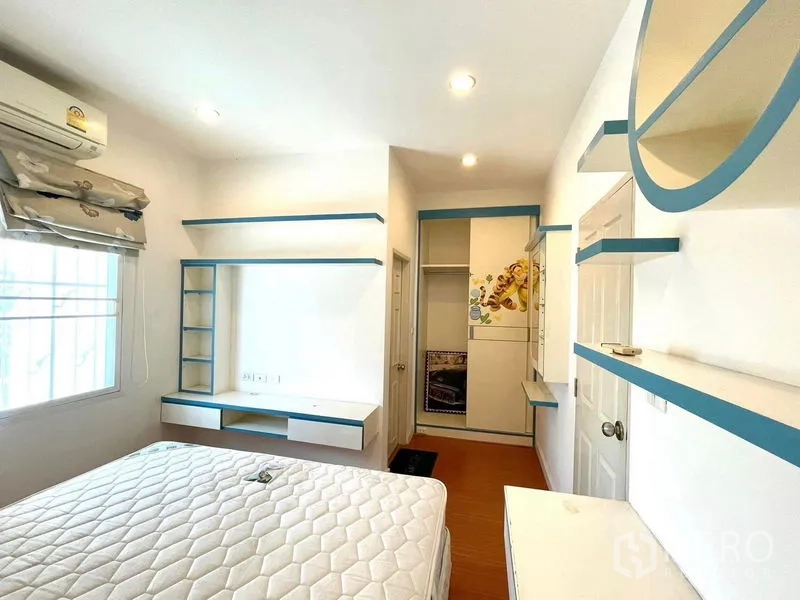 Townhouse for rent in Saphan Sung, Bangkok - Bedroom featuring blue‑trim shelving, work desk and a window with patterned blinds.