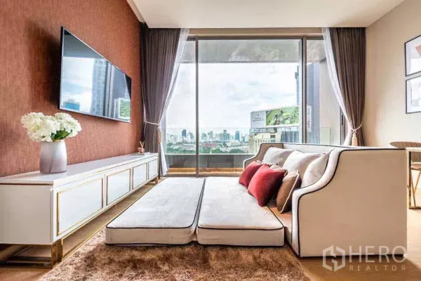 公寓 出租或出售在Bang Rak, Bangkok - 现代客厅，墙挂电视与沙发，推拉落地门外是城市天际线。