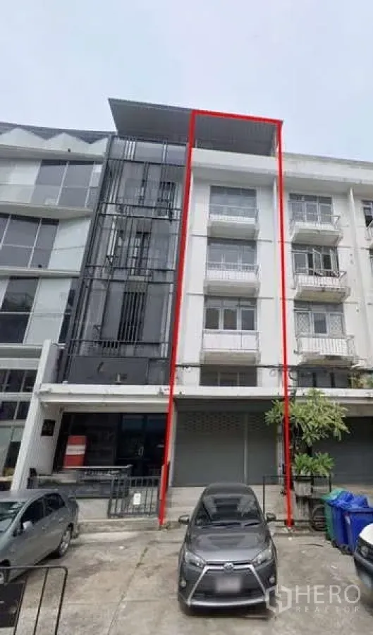 Shophouse for rent in Bang Na, Bangkok - Four-storey shophouse facade with balconies and a parking bay marked by red lines.