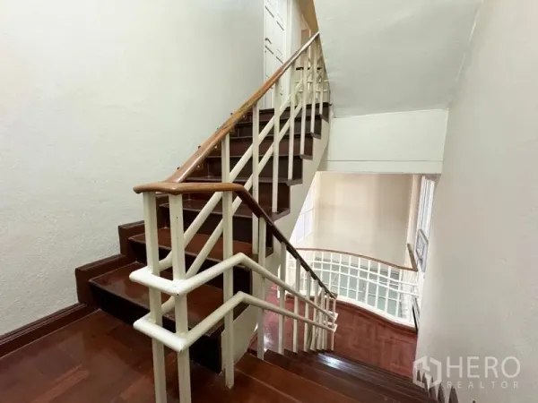 Townhouse for rent or sale in Suan Luang, Bangkok - Staircase with wooden steps and white railings in a multi-storey townhouse