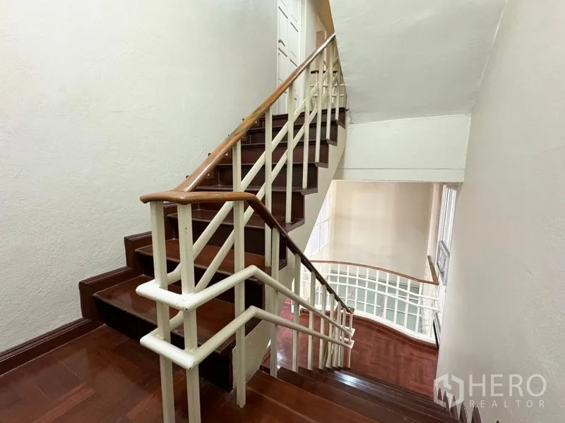 Townhouse for rent or sale in Suan Luang, Bangkok - Staircase with wooden steps and white railings in a multi-storey townhouse