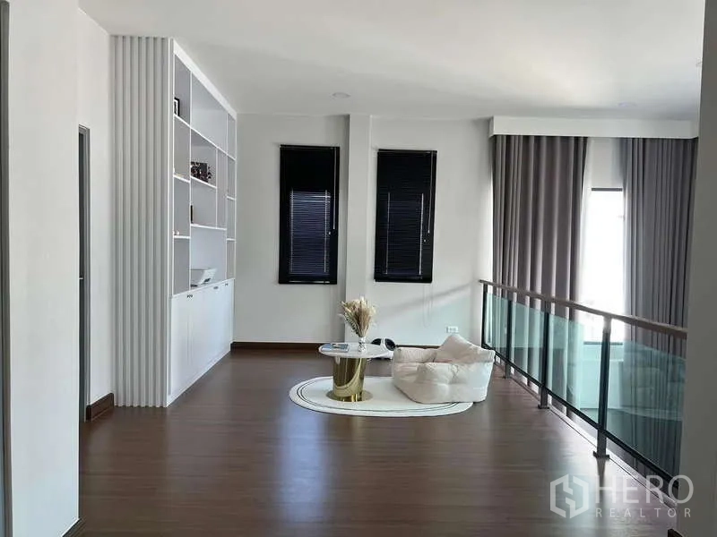 独立式住宅 出租在Bang Phli, Samut Prakan - 二楼家庭起居区，玻璃栏杆与内置书架