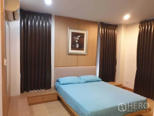 公寓 出租在Watthana, Bangkok - 主卧配双人床、遮光窗帘与木质墙面，氛围温暖。