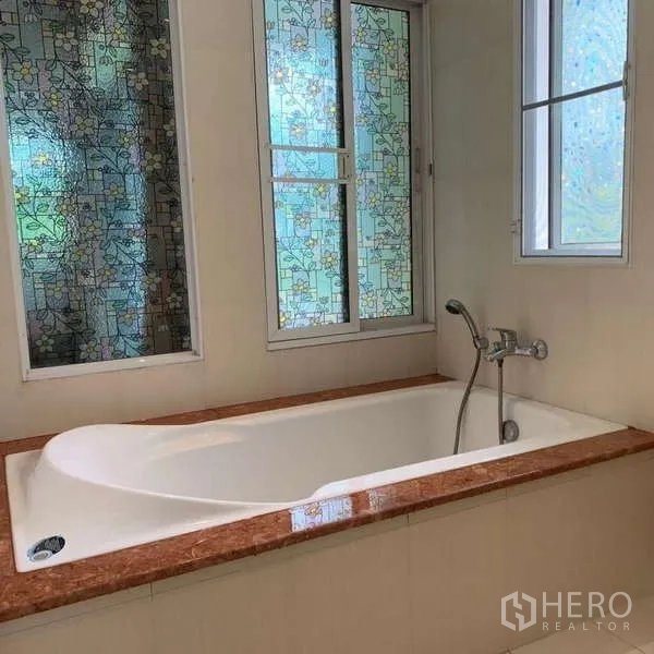 Detached House for rent in Lat Krabang, Bangkok - Bathroom with built-in bathtub and patterned frosted windows.