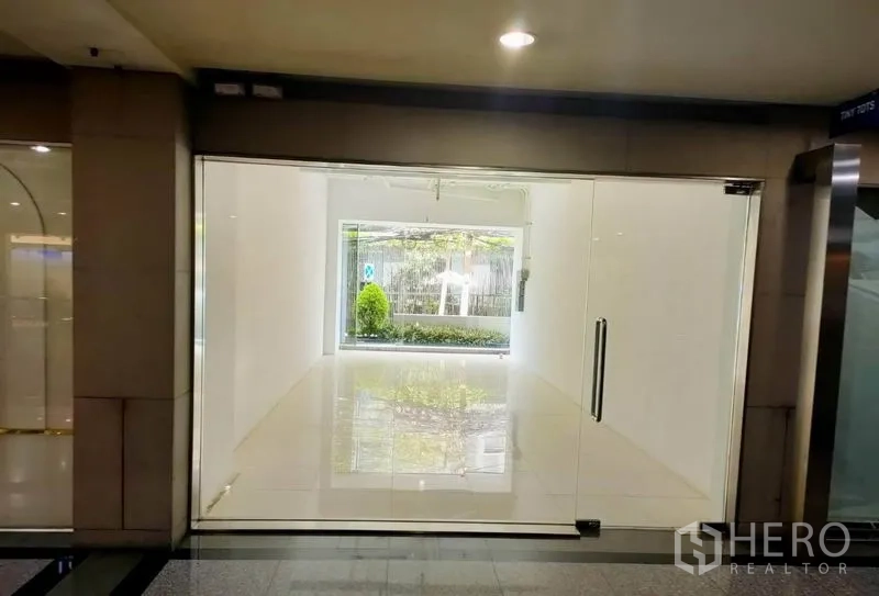 Retail Space for rent in Khlong Toei, Bangkok - Empty 31 sqm retail unit with full-height glass storefront, white walls, glossy tile floor, and landscaped view near BTS Thonglor in Bangkok.