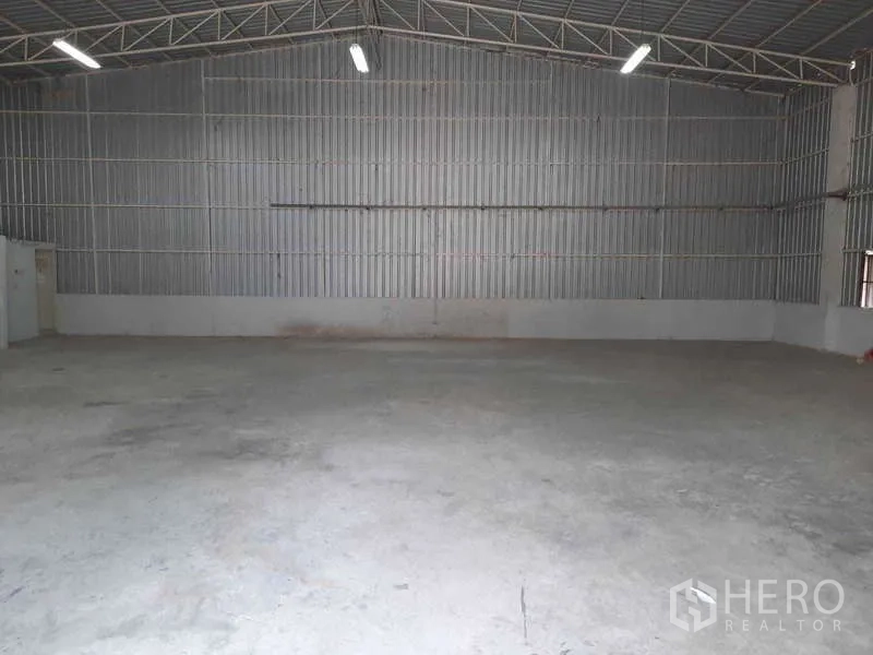 货栈 出租在Khlong Luang, Pathum Thani - 混凝土地面与波纹金属墙面的空置库厅，线性照明适合安装货架。