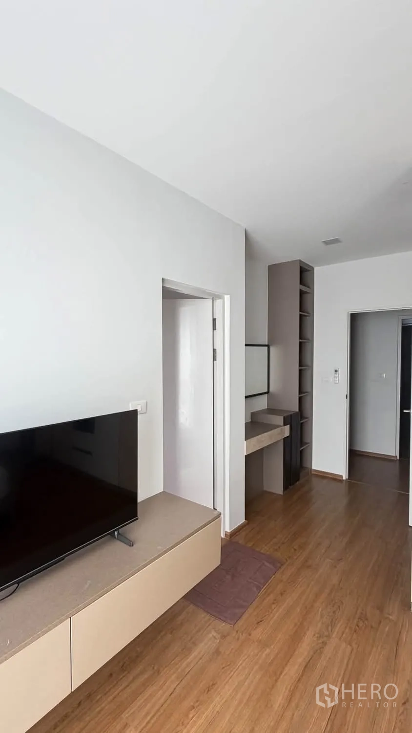 Townhouse for rent in Bang Phli, Samut Prakan - Room with a built-in TV console, desk, shelving, and wood floors.