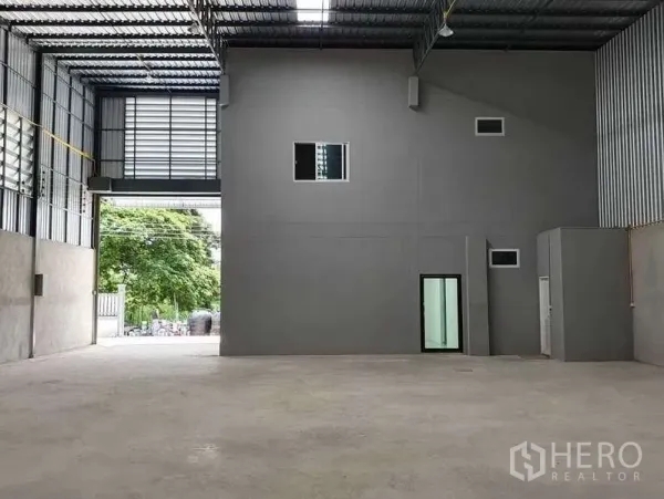 Warehouse for rent in Pathum Thani - Spacious high-ceiling warehouse interior with steel roof, large roller shutter access and internal office rooms.