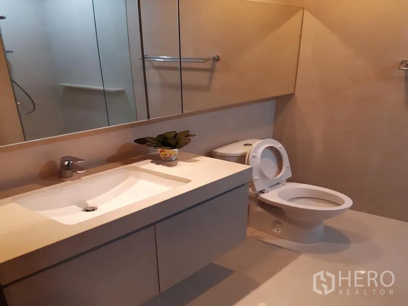公寓 出租在Watthana, Bangkok - 紧凑卫生间，带洗手台、镜柜和坐便器。