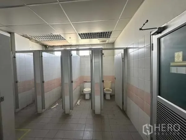 Factory for rent or sale in Thanyaburi, Pathum Thani - Industrial restroom with tiled stalls and partition doors inside the factory.