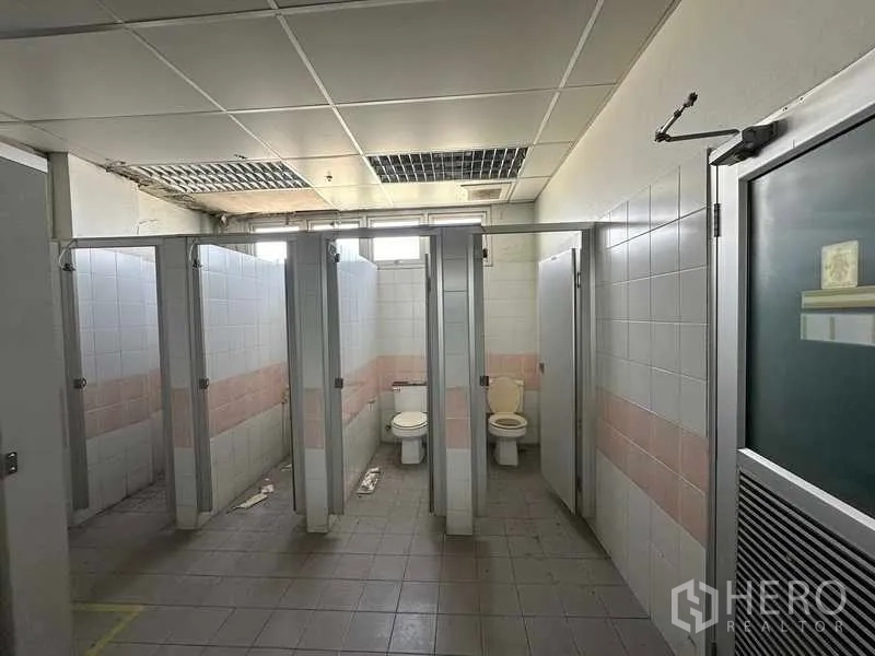 Factory for rent or sale in Thanyaburi, Pathum Thani - Industrial restroom with tiled stalls and partition doors inside the factory.