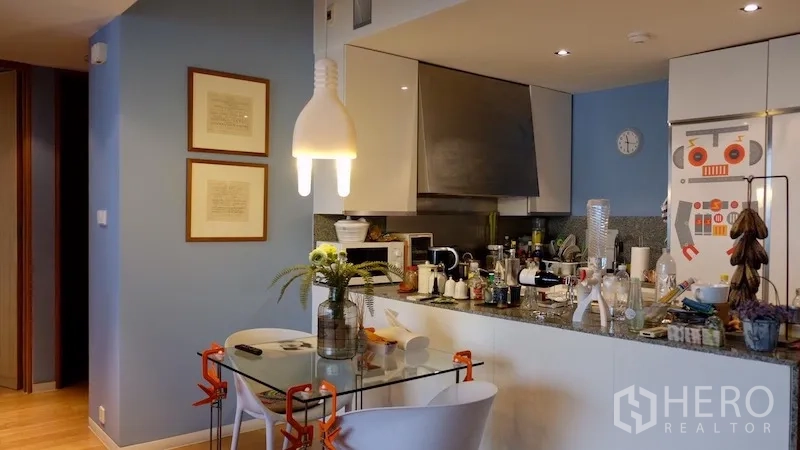 Condominium for rent or sale in Sathon, Bangkok - Modern kitchen with breakfast bar, pendant lights and a glass dining table.