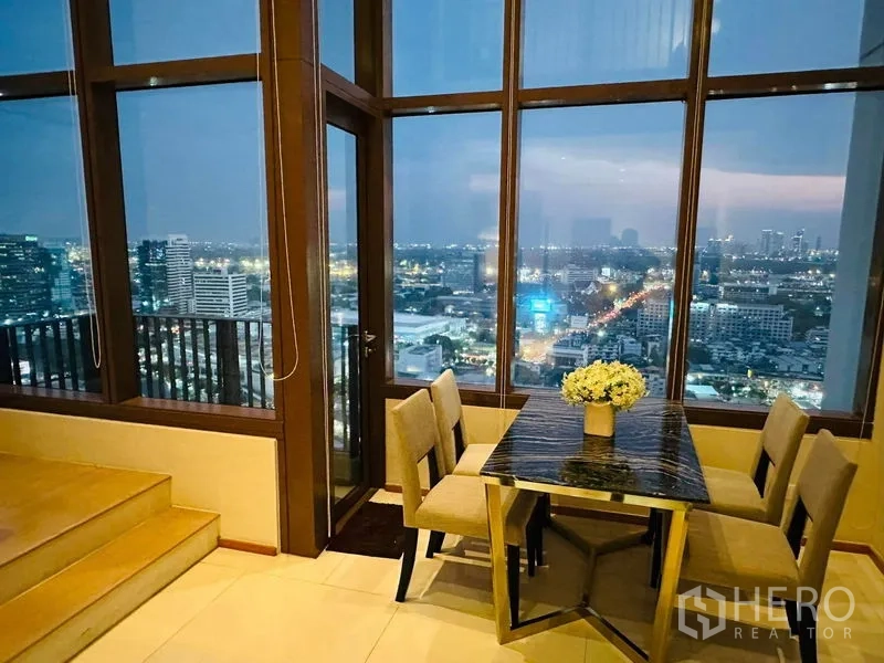 公寓 出租在Bangkok - 阳台门旁的转角餐桌，三面落地玻璃与城市景观
