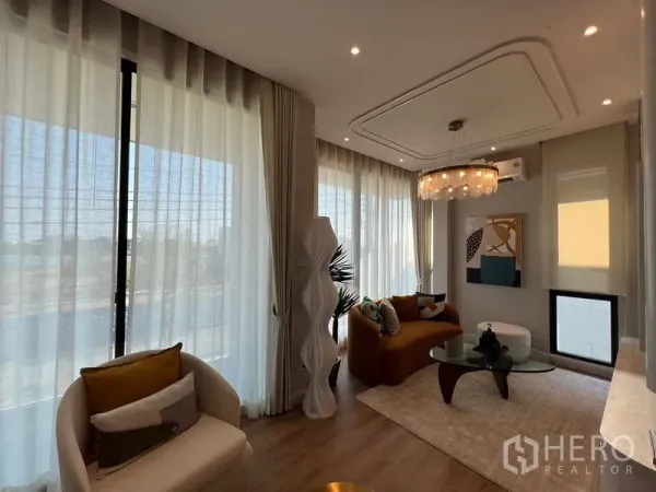 บ้าน ขายในSaphan Sung, Bangkok - ห้องนั่งเล่นรับแสง พร้อมผ้าม่านโปร่ง โคมระย้า โซฟาสมัยใหม่และโต๊ะกระจก ในบ้านเดี่ยว สะพานสูง กรุงเทพฯ