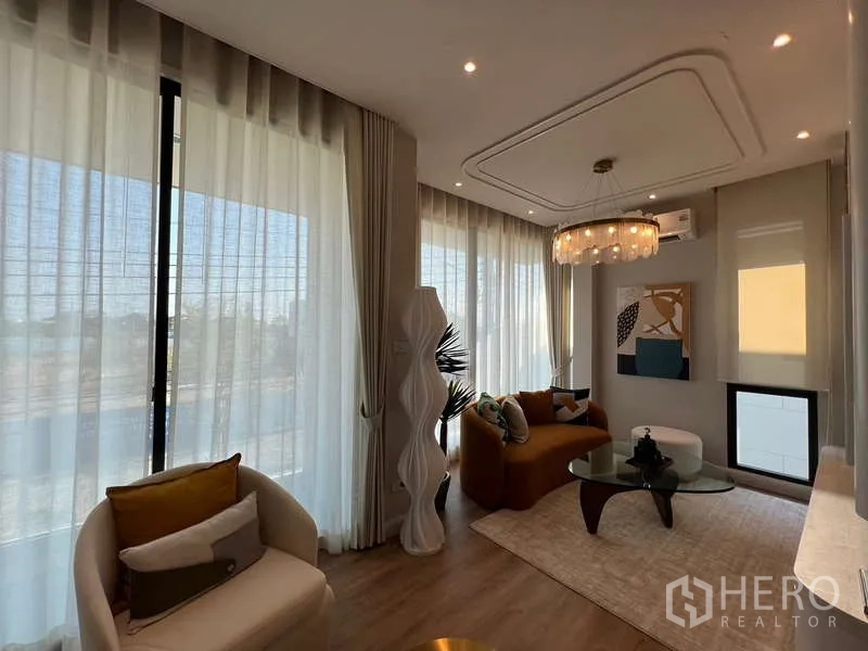 บ้าน ขายในSaphan Sung, Bangkok - ห้องนั่งเล่นรับแสง พร้อมผ้าม่านโปร่ง โคมระย้า โซฟาสมัยใหม่และโต๊ะกระจก ในบ้านเดี่ยว สะพานสูง กรุงเทพฯ