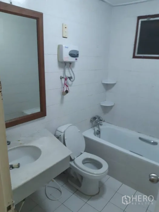 联排别墅 出租在Khlong Toei, Bangkok - 白色瓷砖浴室，浴缸、坐便、洗手台和热水器齐全。