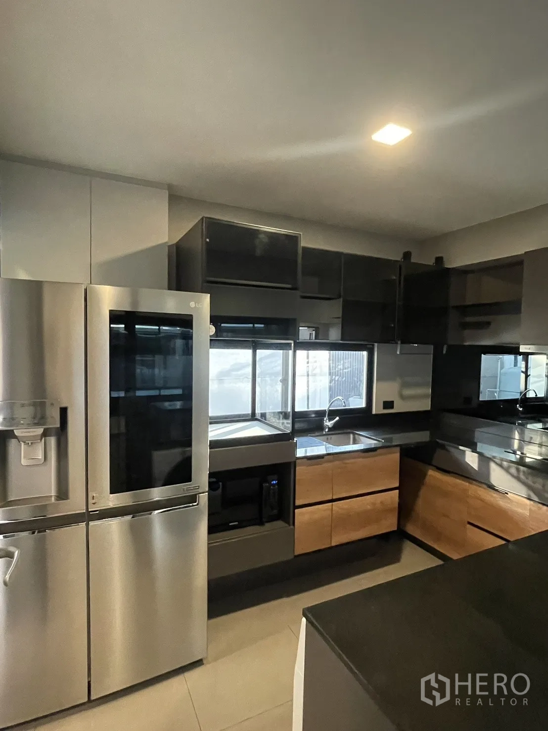 Townhouse for sale in Bang Phli, Samut Prakan - Contemporary U-shaped kitchen with stainless refrigerator and black countertops.