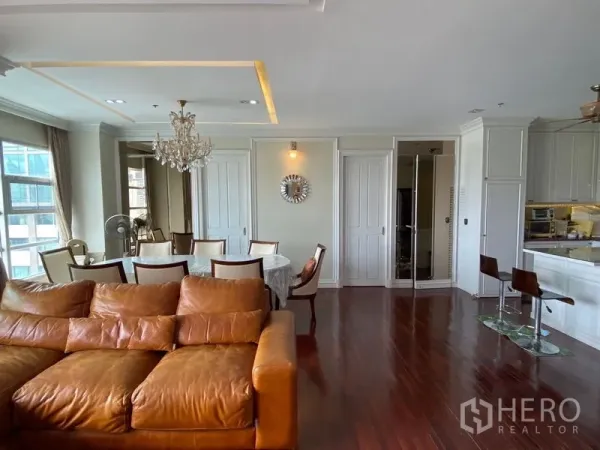 Condominium for rent in Ratchathewi, Bangkok - Open-plan living and dining area with leather sofa, chandelier, and polished wood floors in a Ratchathewi condo.