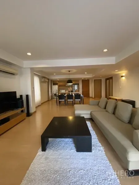 房间 出租在Watthana, Bangkok - 宽敞的客餐厅一体空间，木地板，转角沙发、茶几与地毯。