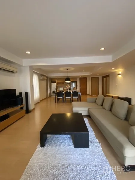 房间 出租在Watthana, Bangkok - 宽敞的客餐厅一体空间，木地板，转角沙发、茶几与地毯。