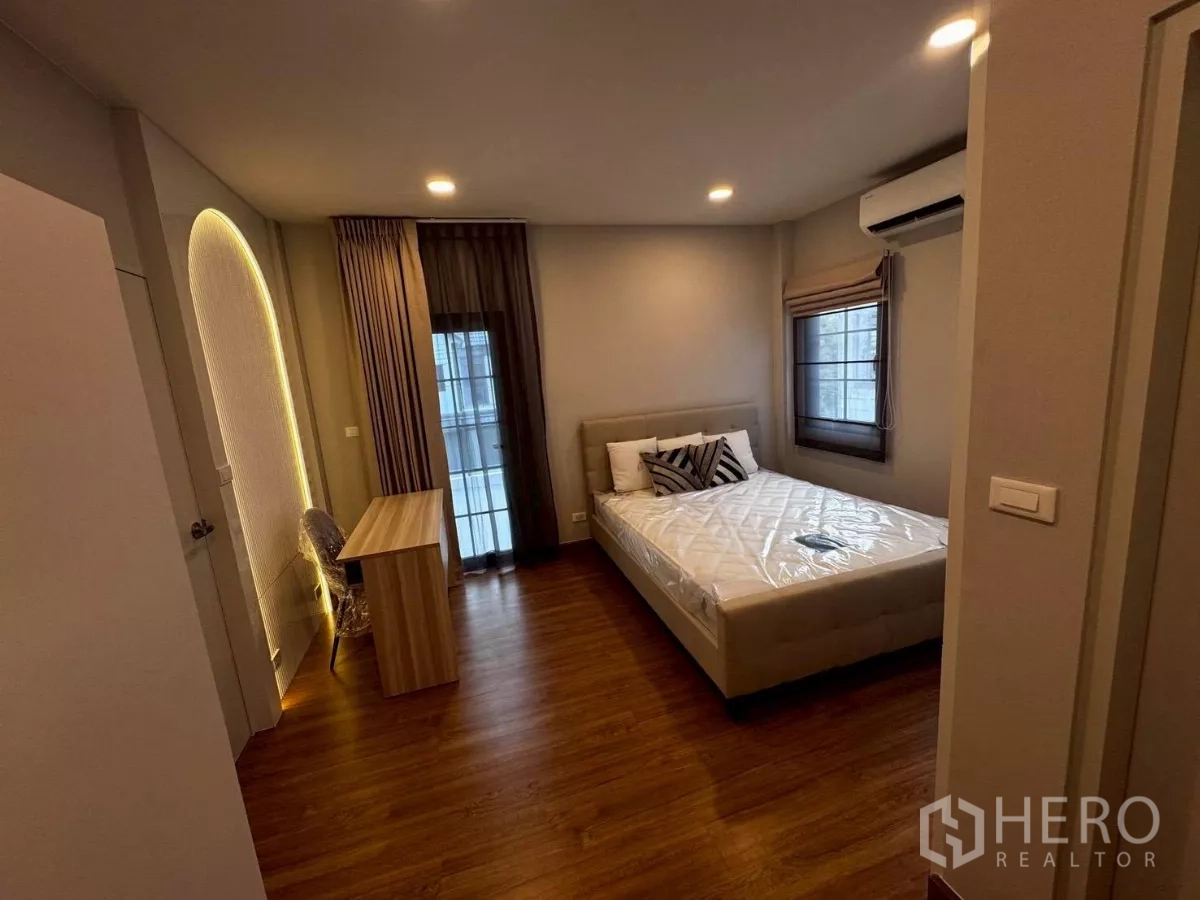 บ้าน ให้เช่าในBang Phli, Samut Prakan - ห้องนอนเตียงคู่พร้อมโต๊ะทำงานริมหน้าต่าง ไฟสลัว และเครื่องปรับอากาศ