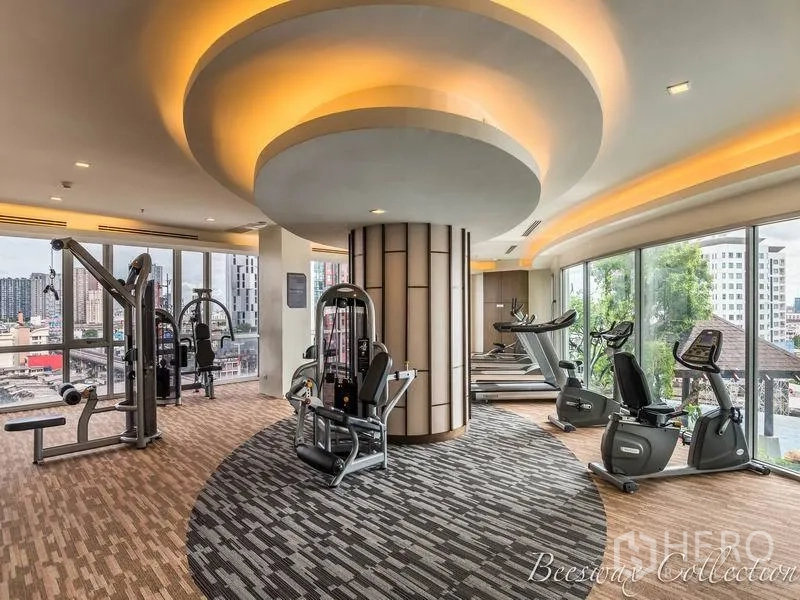 Condominium for rent in Watthana, Bangkok - Well‑equipped fitness room with cardio and weight machines under cove lighting and skyline views.