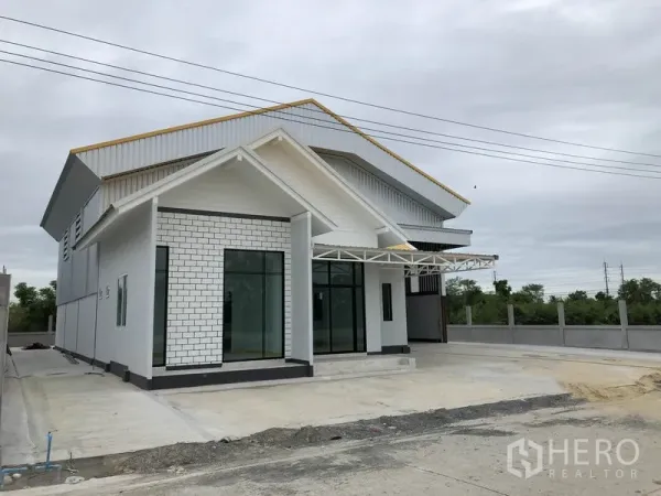 Factory for rent or sale in Sai Noi, Nonthaburi - Angled exterior of modern factory showing large office windows and a covered entry canopy.