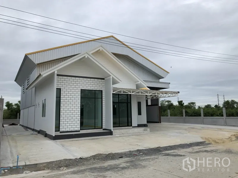 Factory for rent or sale in Sai Noi, Nonthaburi - Angled exterior of modern factory showing large office windows and a covered entry canopy.
