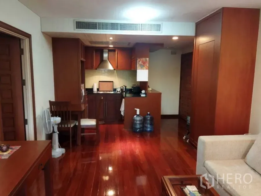 公寓 出租在Pathum Wan, Bangkok - 开放式起居区，抛光木地板与带抽油烟机的小厨房。