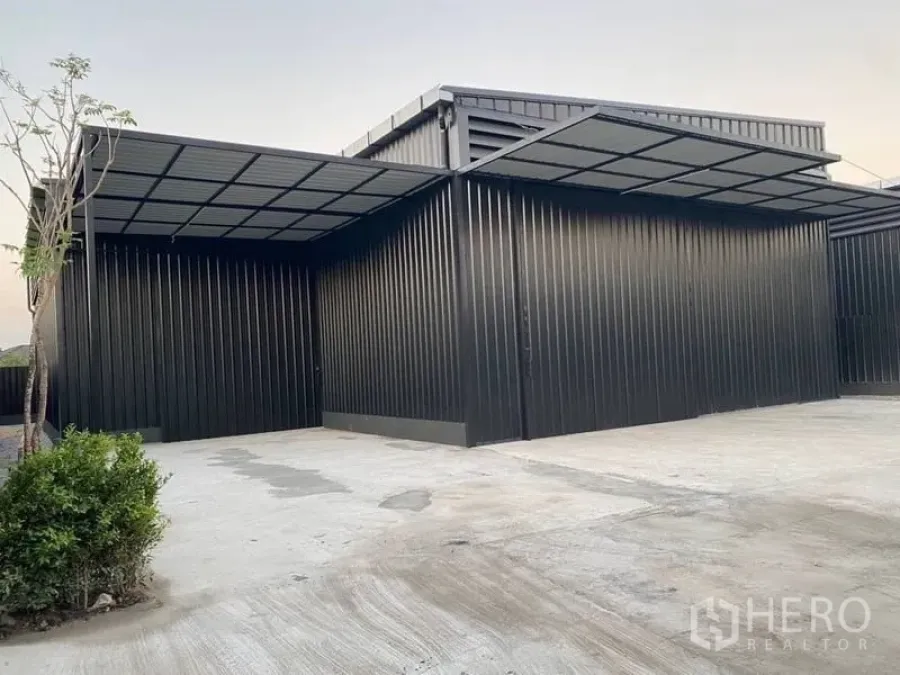 Warehouse for rent in Wang Thonglang, Bangkok - Front canopy and parking apron of black steel warehouse with landscaping beside the concrete yard.