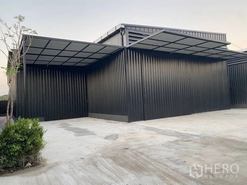 Warehouse for rent in Wang Thonglang, Bangkok - Front canopy and parking apron of black steel warehouse with landscaping beside the concrete yard.