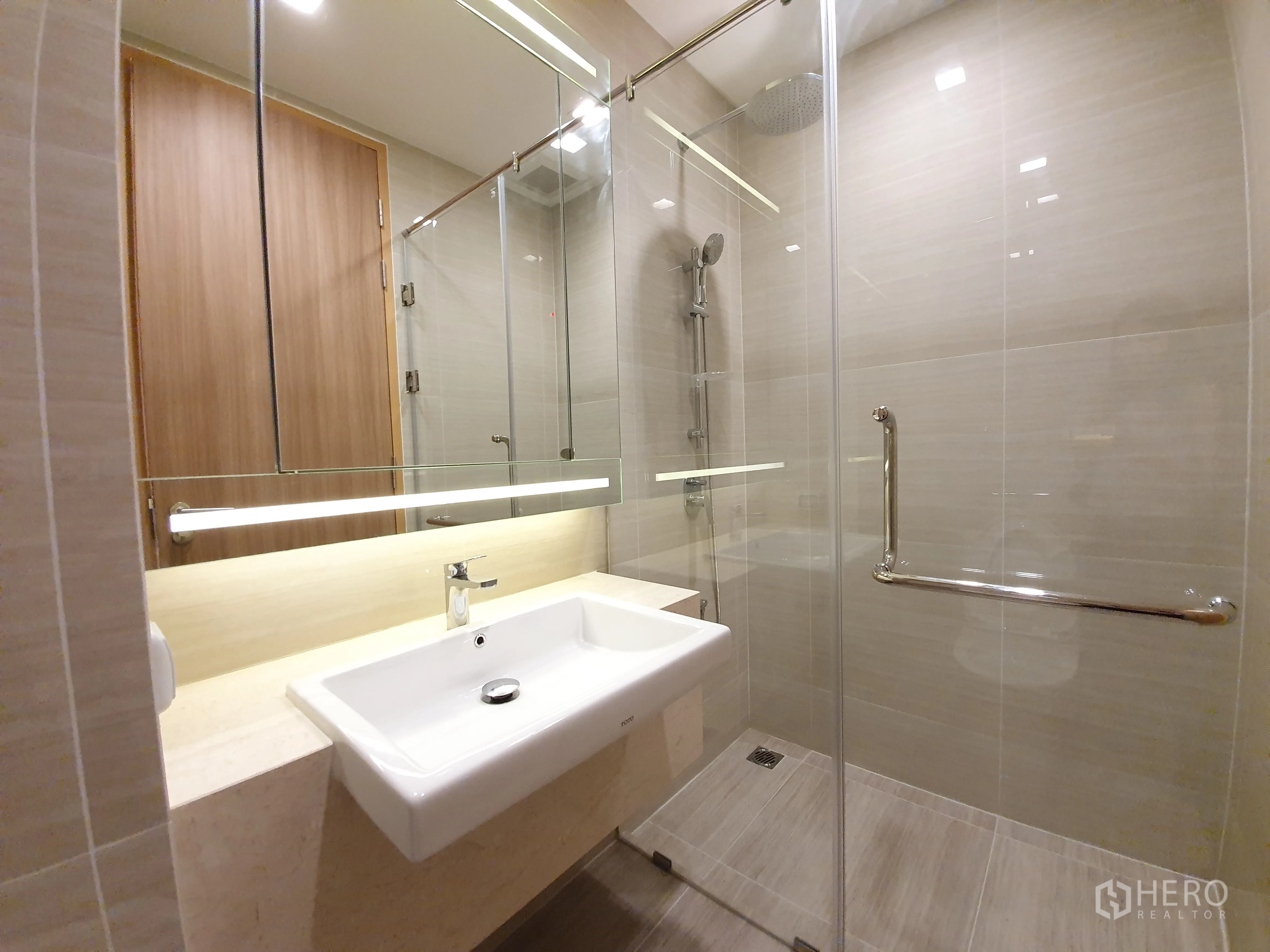 Condominium for rent in Watthana, Bangkok - Contemporary bathroom with glass-enclosed rain shower, large mirror and sleek vanity sink.