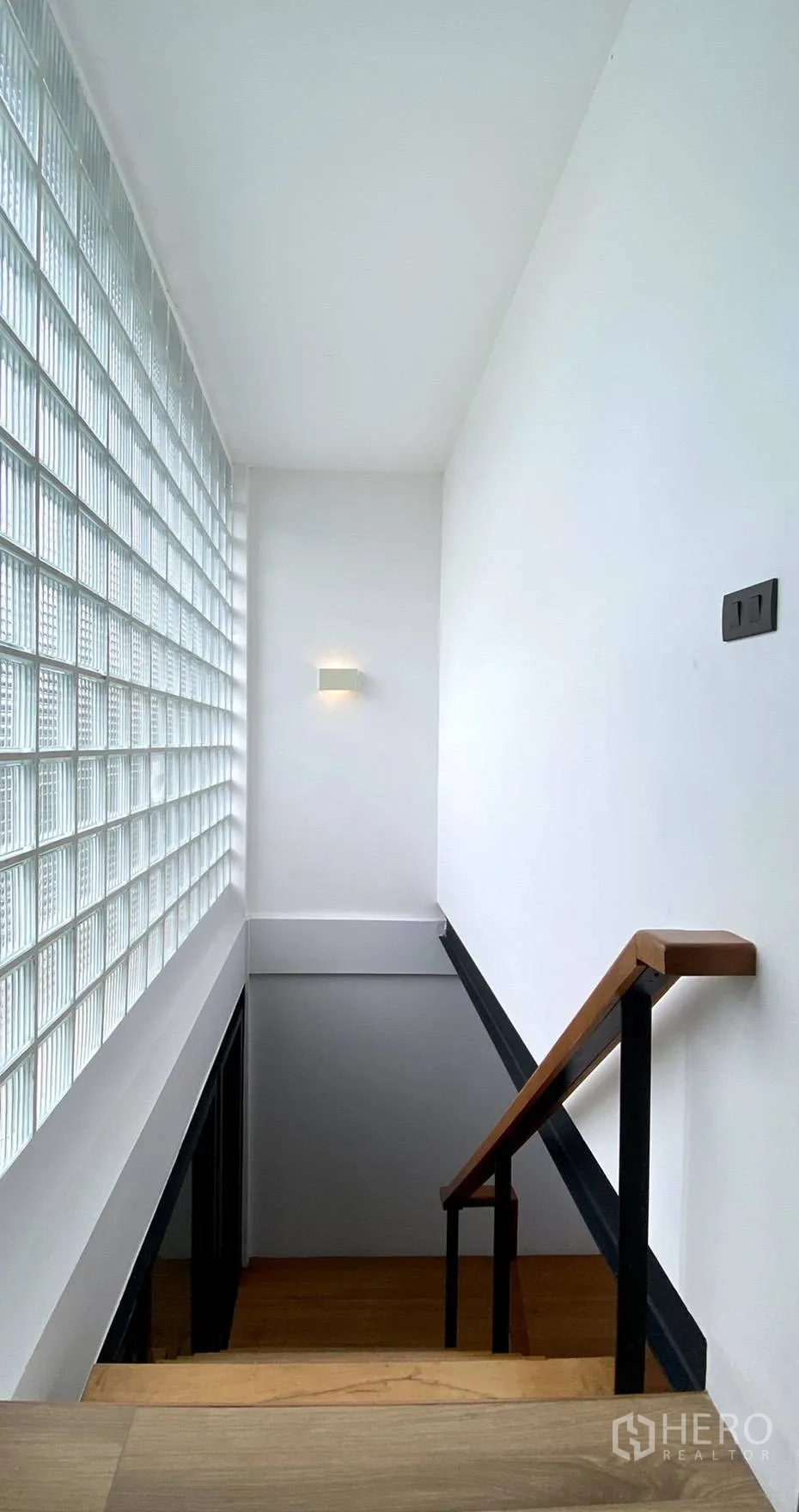 Townhouse for rent in Watthana, Bangkok - Stairwell with glass-block wall bringing natural light and a wooden handrail.