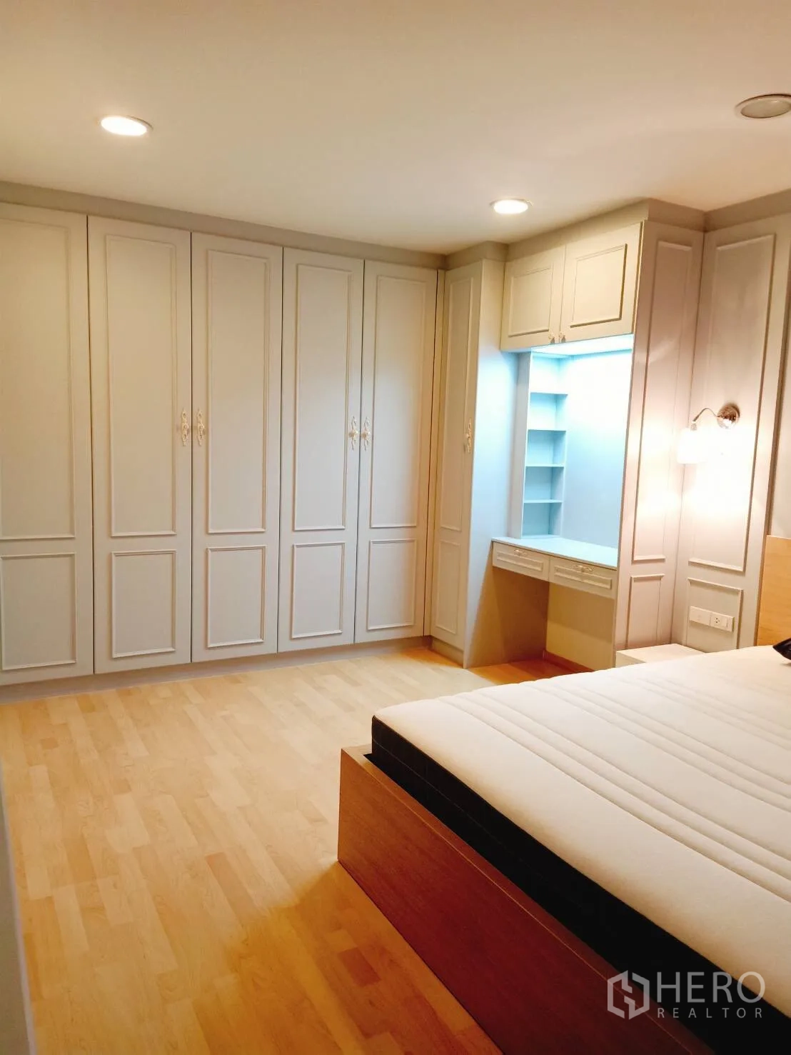 Townhouse for rent in Suan Luang, Bangkok - Primary bedroom with a wall of fitted wardrobes, vanity and light wood flooring