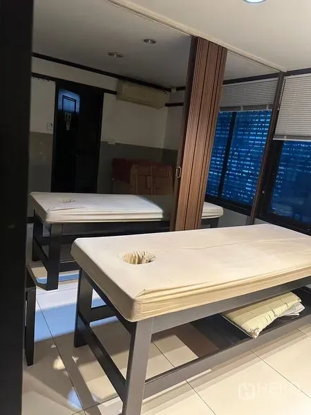 Shophouse for rent in Phra Khanong, Bangkok - Bright treatment room with two massage tables, windows and a folding partition.