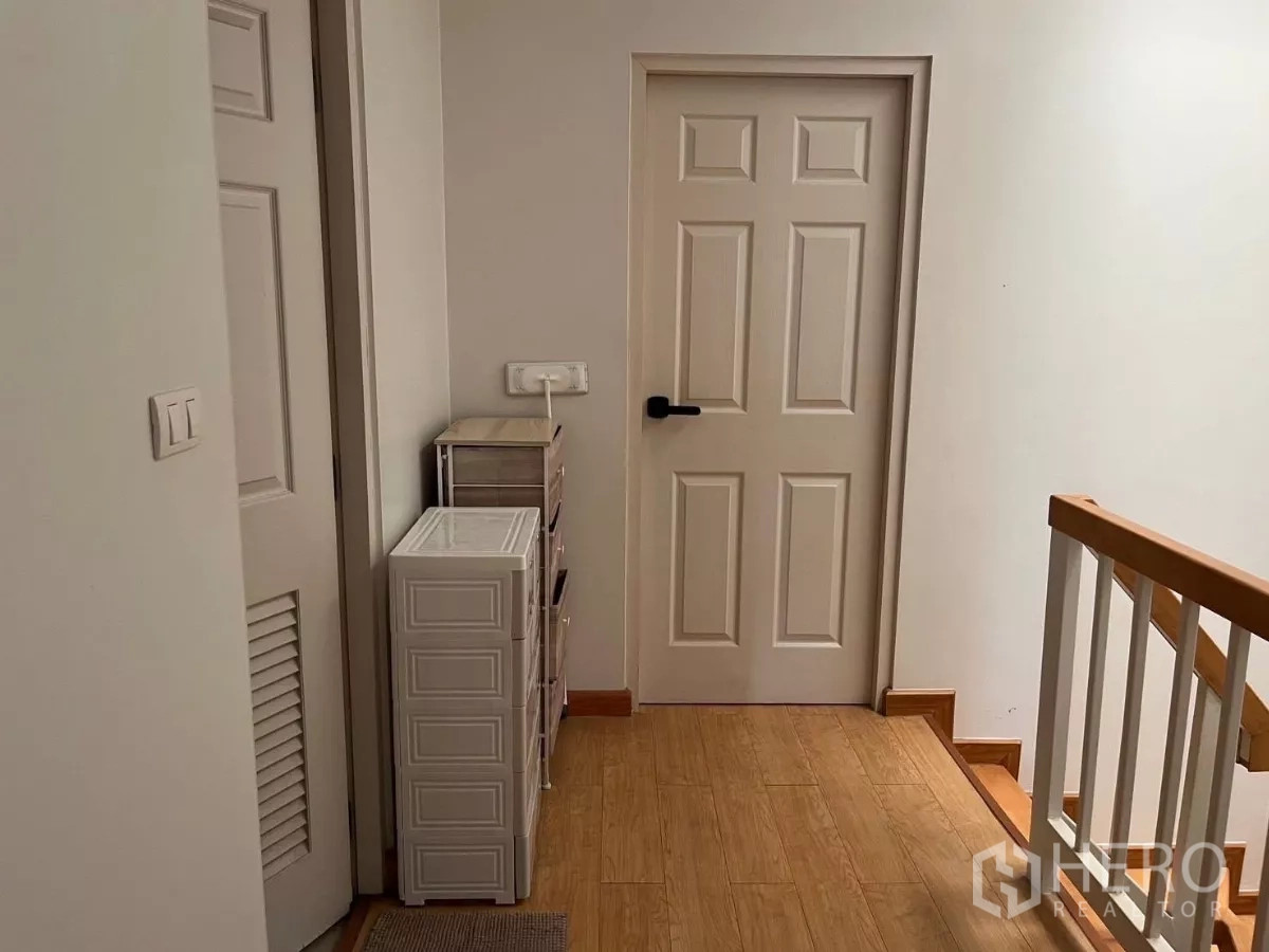 Townhouse for rent in Bang Kho Laem, Bangkok - Upper corridor with storage drawers beside cream door and stair rail.
