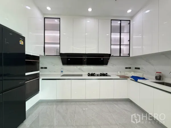 Condominium for sale in Watthana, Bangkok - Sleek white U-shaped kitchen with gas hob, hood, and glossy cabinets.
