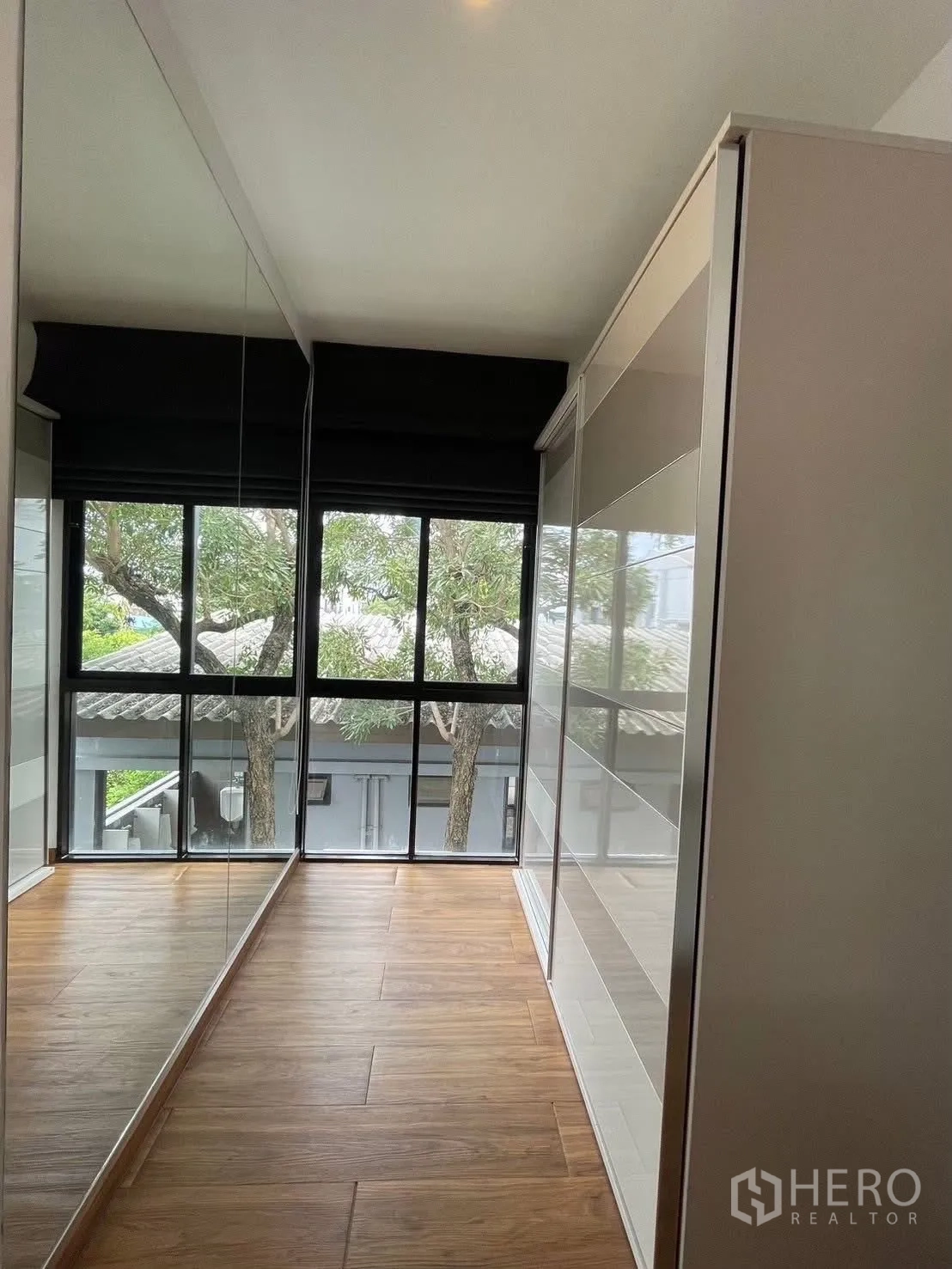 Townhouse for rent in Suan Luang, Bangkok - Walk-in closet corridor with mirrored wardrobes and a wide window.