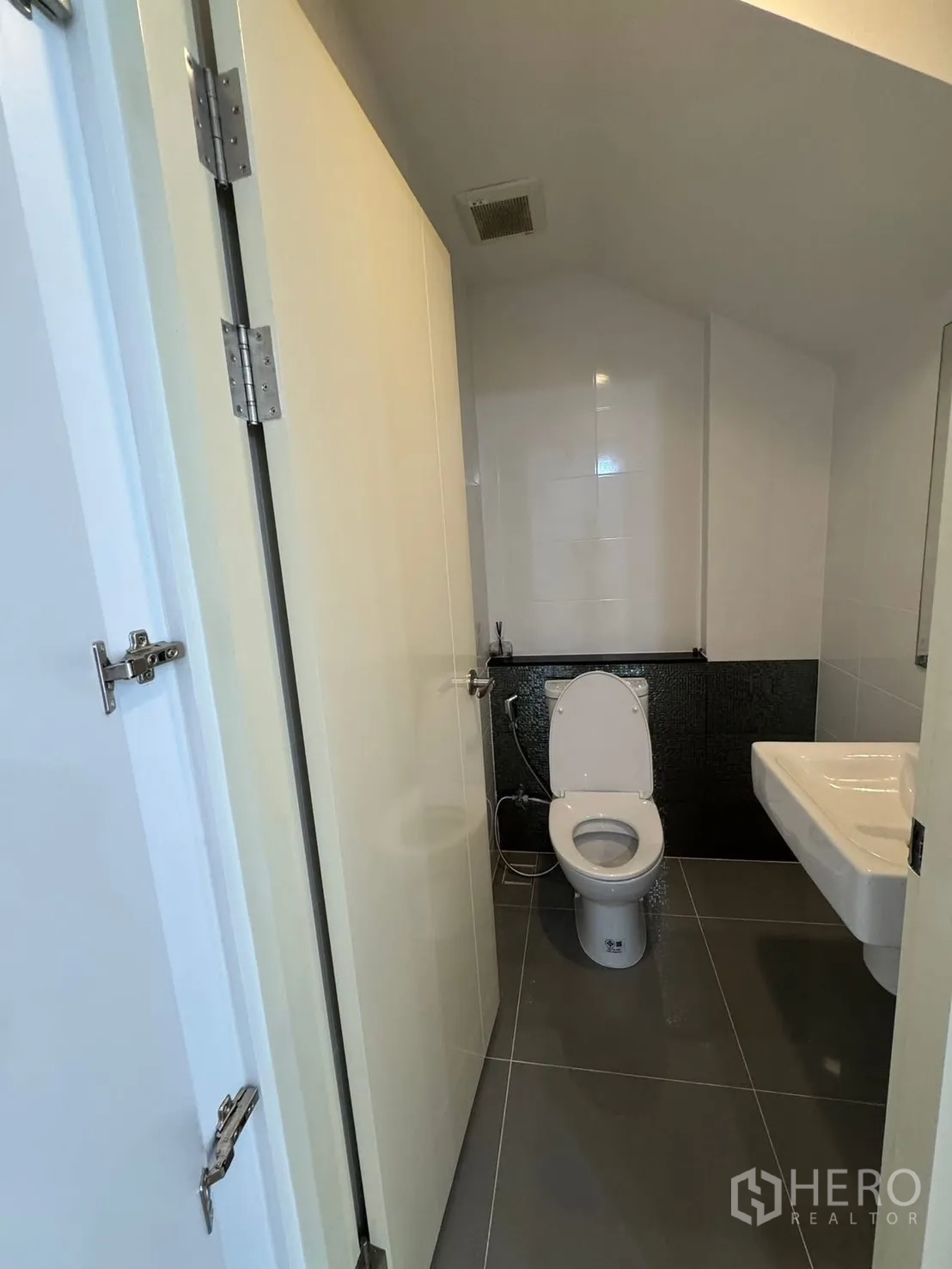 Townhouse for rent in Saphan Sung, Bangkok - Compact guest bathroom with toilet and wall-mounted sink.