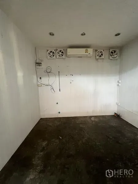Retail Space for rent in Khlong Toei, Bangkok - Small white retail interior with recessed lights, wall air conditioner and multiple ventilation fans over a concrete floor.