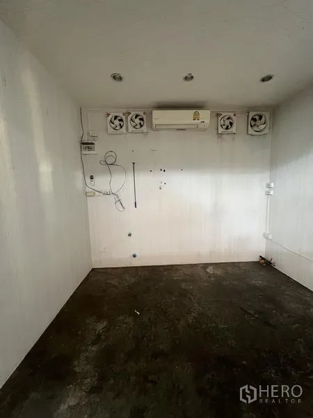 Retail Space for rent in Khlong Toei, Bangkok - Small white retail interior with recessed lights, wall air conditioner and multiple ventilation fans over a concrete floor.
