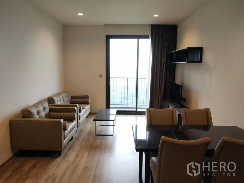公寓 出租在Chatuchak, Bangkok - 明亮的客餐厅，沙发与餐桌，落地推拉门通向阳台。