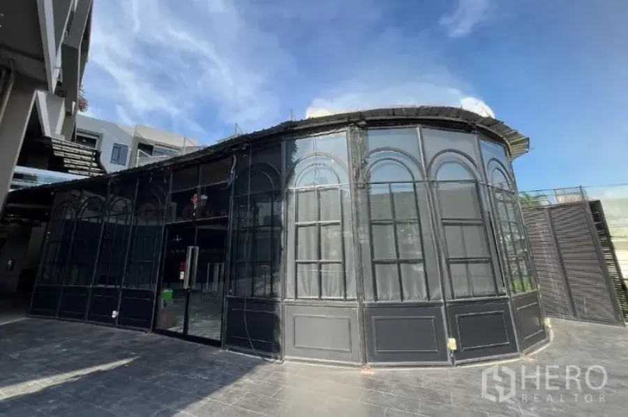 Retail Space for rent - Curved glass frontage of the unit with black frames and a spacious paved apron.