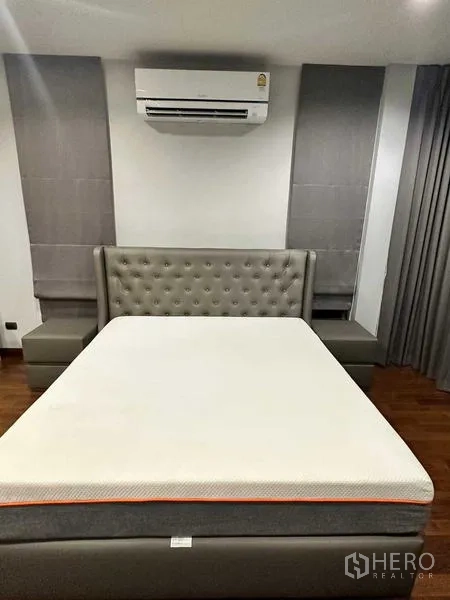 Detached House for rent in Lat Krabang, Bangkok - Bedroom with tufted headboard, air conditioner, grey drapes and wood flooring.