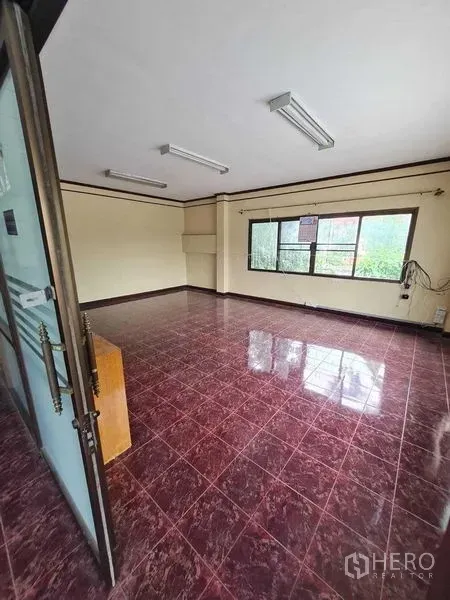 Warehouse for rent in Bang Yai, Nonthaburi - Empty office with maroon floor tiles, large window and fluorescent lights.