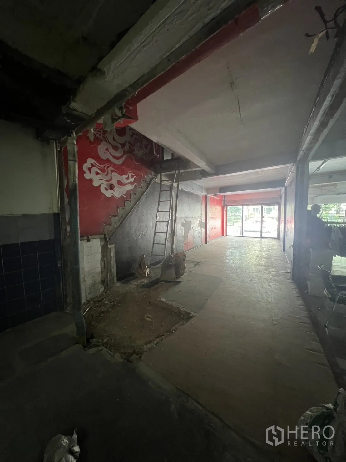 Shophouse for rent in Khlong Toei, Bangkok - Entry corridor showing a staircase with mural and construction materials in a bare space.