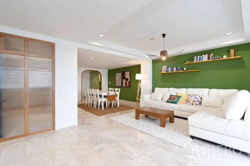 公寓 for rent in Watthana, Bangkok - 宽敞客厅带绿色特色墙、置物架和用餐区。