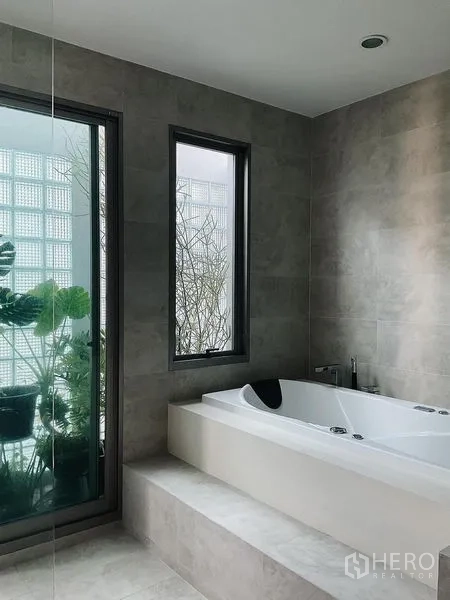 Detached House for sale in Bang Kapi, Bangkok - Spa-style bathroom with soaking tub and windows overlooking greenery.