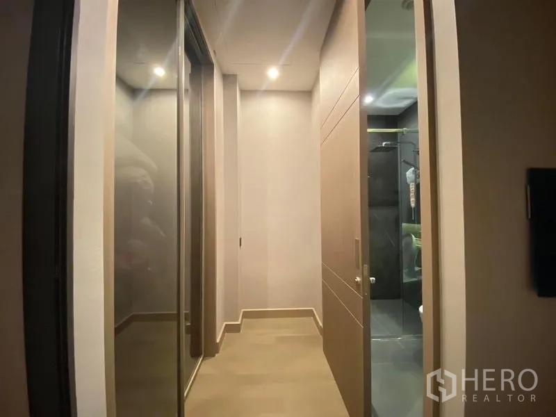 公寓 出租在Huai Khwang, Bangkok - 走廊设镜面衣柜，通向带玻璃淋浴间的现代浴室。